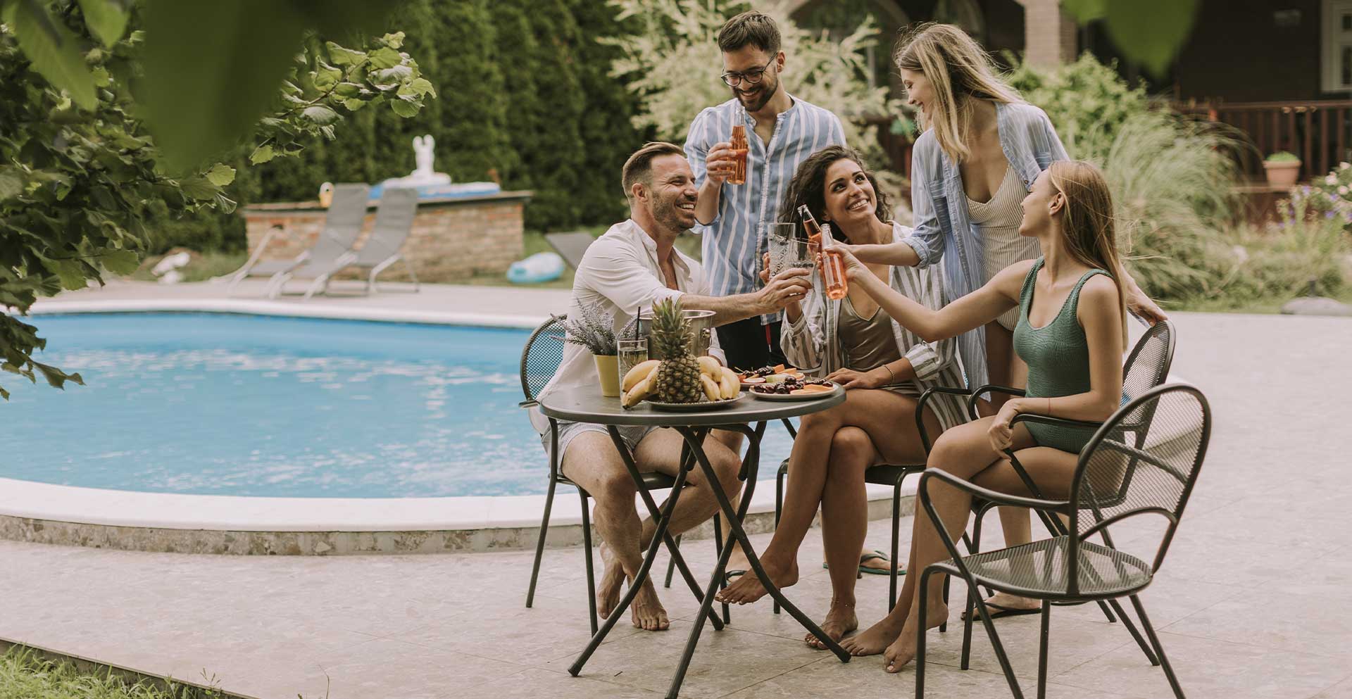 Gruppo di amici che fa un aperitivo a bordo piscina in un giardino protetto dalle zanzare